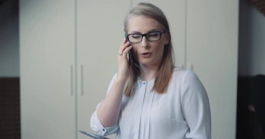 Cep telefonuyla konuşan bir kadın, bir müşteriyle iş meselelerini tartışıyor. Profesyonel iletişim ve müşteri ilişkileri kavramı.