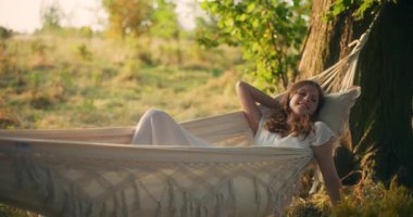 Hayalperest genç bir kız güzel bir gün batımında hamakta nazikçe sallanıyor.