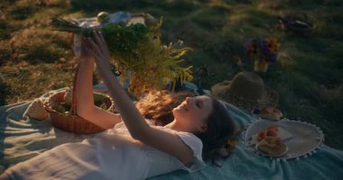 Hayalperest bir genç kız doğada çimenler ve güneş ışığı altında huzur içinde yatıyor.