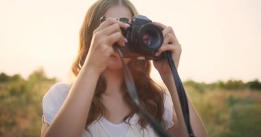 Genç bir kaşif kamerasını tutuyor ve doğanın güzelliğini bir çayırda yakalıyor.