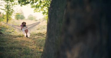 Gülümseyen bir çocuk, güzel bir günbatımında hamakta sessizce düşünür.