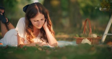 Hayalperest genç bir kız çimenlerin üzerinde uzanıyor ve dışarıda huzurlu bir yaz anının tadını çıkarıyor.