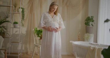 Karnını okşayan hamile bir kadının güzel dekore edilmiş bir odada ilk çocuğunu beklerken..