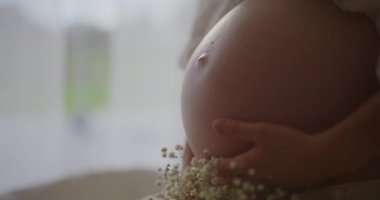 Hamile kadın karnını nazikçe okşar, hamileliğinin sekizinci ayında çocuğunu bekler..