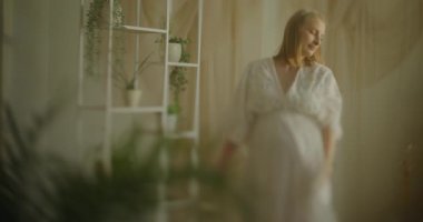 Bebek bekleyen hamile bir kadının portresi. Güzel bir İtalyan tarzı oturma odasında poz verip dans ediyor..