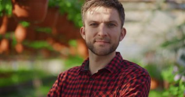 Neşeli bir bahçıvanın portresi serada bitkiler ve fidelerle.