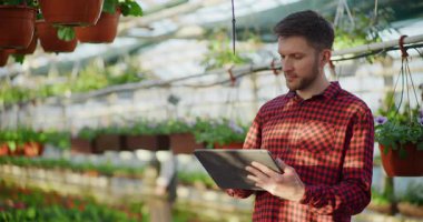 Güzel bir seranın ortasında dijital tabletle çalışan profesyonel bir bahçıvan..