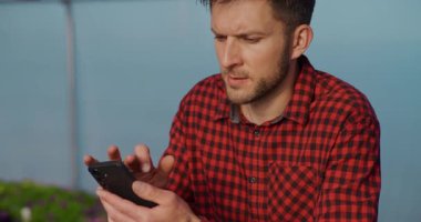 Bahçıvan bir serada çalışırken müşterilerin mesajlarına ve e- postalarına cevap vermek için bir cep telefonu kullanır.