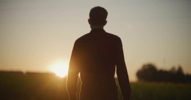 Çiftçinin silueti tarlaların üzerinde güneşin altında yürüyor..