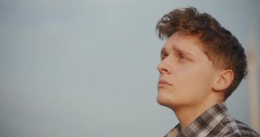 Düşünceli genç bir çiftçi gökyüzüne bakar, kırsal bir zemine karşı kurulmuş, gelecekteki hasat ve doğa harikalarını düşünür..