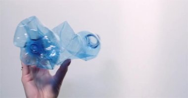 Plastikleri sıralayan, geri dönüşüm sembolü olan plastik bir şişe tutan bir kadın..