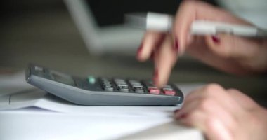 Şirketinin mali kayıplarını hesap makinesi kullanarak hesaplayan bir kadın..