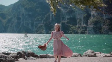 Neşeli bir kadın yürüyor, dönüyor, güzel bir deniz manzarasında dans ediyor, güneşli bir günün tadını çıkarıyor..