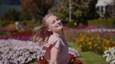 Güzel çiçeklerle dolu bir alanda dans eden neşeli bir kadın mutluluk ve memnuniyeti ifade eder..