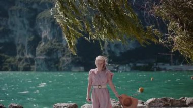 Mutlu bir kadın manzaralı bir sahil yolunda yürüyor, okyanus manzarasının ve güzel deniz manzarasının tadını çıkarıyor..