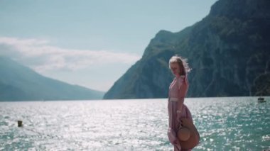 Güzel dağların arka planında duran bir kadının huzurlu manzarası ve kıyıda mavi suyu olan deniz..