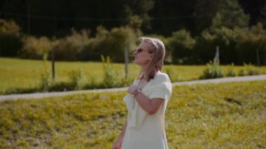 Dalgın bir kadın, bereketli bitki örtüsüyle çevrili manzaralı bir ormanda huzur içinde yürüyor..