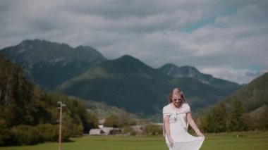 Düşünceli bir kadın manzaralı bir Alp manzarasının önünde geziniyor..