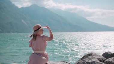 Neşeli bir kadın güzel bir dağ manzarası ve mavi bir deniz ile resim yapar. Sahne mutluluğu yakalar ve güzelliği..