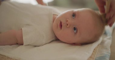 Sevimli erkek bebek, annesi tarafından taranıyor, yakın plan. Bebek bakımı rutini, banyodan sonra nazik hareketlerle..