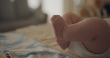 Küçük parmaklarıyla küçük parmaklarını keşfederken ve dokunurken bir oyun matı üzerinde hareket eden bebek ayaklarının sevimli yakın çekimi.