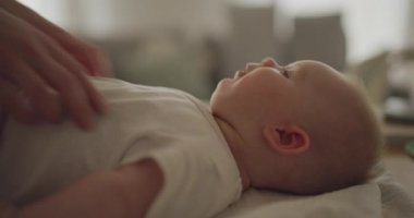 Bir anne, bezini değiştirirken oğlunu neşeyle gıdıklıyor, onu güldürüyor ve neşeyle bez değiştirirken gülümsüyor..