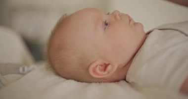 Anne bebeğe bakıyor, saçlarını tarıyor ve banyodan sonra kafa derisini yüzüyor..