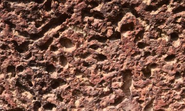 Kahverengide birçok delik var. Eski kayanın turuncu ve kırmızı yüzeyi var.