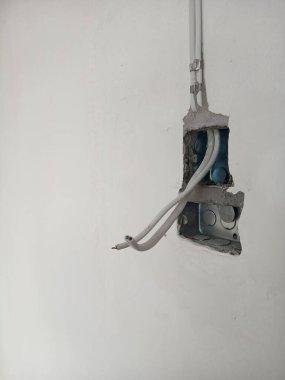 Evdeki gri duvardaki elektrik prizi kutusu için boşluklardaki kablolar ve boşluklar