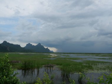 Dağın tepesinde gri Cumulonimbus bulut oluşumları, sulak alanlarda hareket eden Nimbus, Tayland 'daki Khao Sam Roi Yot Milli Parkı' na düşen yağmur bulutu, göl manzarası.