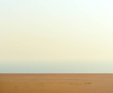 Arkaplanda gün doğumunda gökyüzünde mavi ve sarı ışık bulunan ürün yerleştirme için boş kahverengi ahşap masa yüzeyi