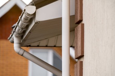 Evin ön cephesindeki drenaj boruları arka plandaki tuğla evin arka planına karşı.