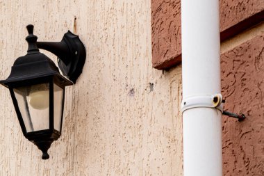 Kanalizasyon borusu ve fener sıva kaplı bir evin ön cephesinde.