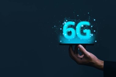 İş adamı elinde hologram 6G dijital teknolojili bir akıllı telefon tutuyor, dünyadaki bilgilere erişim sağlıyor. 5G kablosuz internet ağı kavramı veya IOT, yüksek hızlı iletişim bağlantısı.