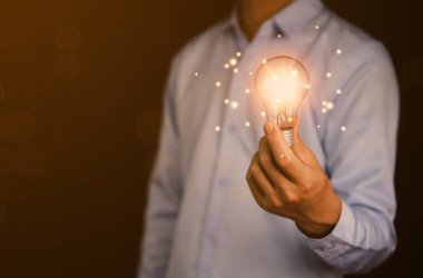 İş adamı elinde bir ampul grafik dijital teknoloji soyutlaması tutuyor. Yaratıcı ve yenilikçi bir fikir hayal et. İş dünyasındaki beyin fırtınasından beyin fırtınasına. Geliştirme, büyüme ve başarı stratejileri
