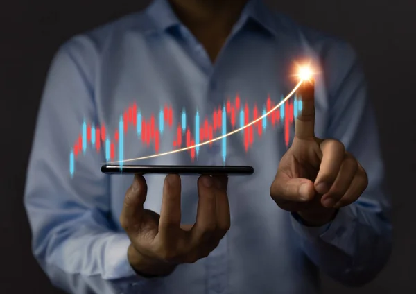 businessman using a tablet to plan a strategy that shows a positive digital technology graph chart. The concept is growing stocks, investing, stock marketing, and success.