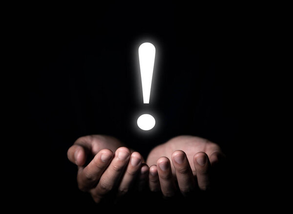 рука показывает белый восклицательный знак. концепция развития бизнеса, предупреждение об ошибках, уведомление, обслуживание и поиск решения. темный фон с копировальным пространством