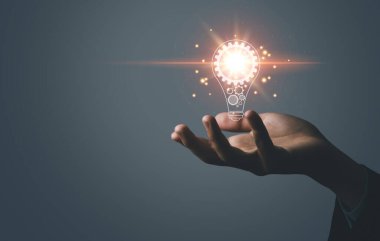 İş adamı elinde bir ampul dijital teknolojisi tutuyor. Yaratıcı ve yenilikçi bir fikir hayal et. İş dünyasındaki beyin fırtınasından beyin fırtınasına. Geliştirme, büyüme ve başarı stratejileri