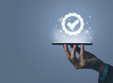 Dijital teknoloji kontrol simgesini gösteren bir akıllı telefonu el ele tutuş. En iyi kalite güvence konsepti En iyi hizmet ürünü performans garantisi ve sektör lideri ISO sertifikaları.