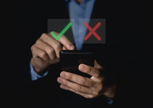 businessman using a smartphone showing checks marks and wrong. concept of deciding to vote to think yes or no Business options for difficult situations true and false symbol