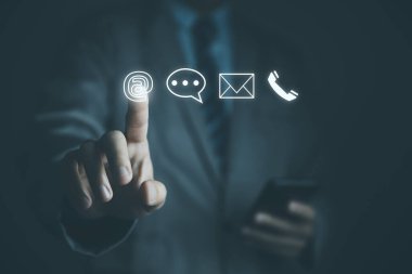 İş adamı telefon, e-posta, adres ve canlı sohbet simgesini gösteren akıllı telefon kullanıyor. Müşteri hizmetleri merkezi bağlantısı için bizimle irtibata geçin. İnternet üzerinden internet üzerinden iletişim