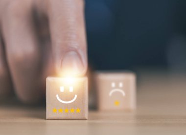 The customer touches a wooden block showing a smiley icon and five stars. Satisfaction survey review concept positive comments The best response service from the product user experience.