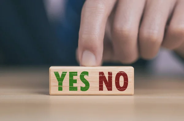 The wooden block shows yes or no letters. The concept of making decisions, voting, and thinking right and wrong. Business options for difficult situations true and false symbol