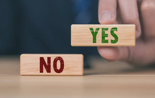 The wooden block shows yes or no letters. The concept of making decisions, voting, and thinking right and wrong. Business options for difficult situations true and false symbol