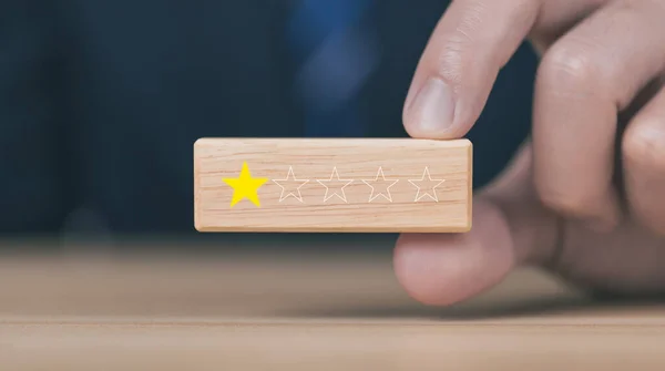 Customer review experience Dissatisfied Choosing 1 star review on wooden block, Negative concept about unhappy businessman, poor service or poor quality.