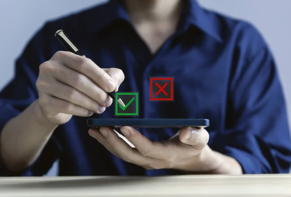 Businessman using smartphone showing right and wrong symbols The idea is to decide to vote. yes or no decision and business alternatives for difficult situations. true and false symbol