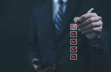 Listedeki bir kutuda kırmızı işaretli bir kalemi tutan işadamı sanal ekranda göster. İş Anketi öğeleri ve anketlerindeki kontrol listesi fikirleri. Boşluğu kopyala