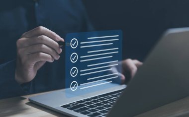 Listedeki bir kutuda kırmızı işaretli bir kalemi tutan işadamı sanal ekranda göster. İş Anketi öğeleri ve anketlerindeki kontrol listesi fikirleri. Boşluğu kopyala