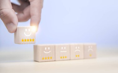 The customer touches a wooden block showing a smiley icon and five stars. Satisfaction survey review concept positive comments The best response service from the product user experience.