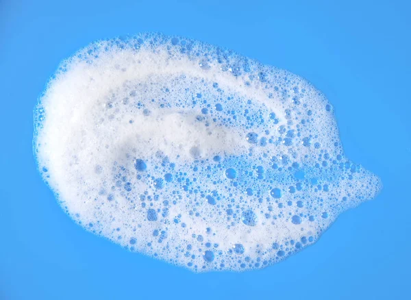 top view liquid white foam from soap or shampoo or shower gel. Abstract bubbles. isolated on a blue background